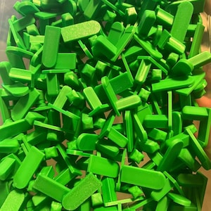 Puede incluir: Una gran pila de separadores de baldosas de plástico verde brillante. Los separadores son de varias formas y tamaños, incluyendo cuadrados, rectángulos y triángulos.