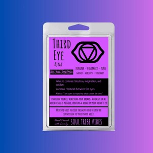 Op de afbeelding: Een paars en zwart kaarsetiket met de woorden "Derde Oog Ajna" en "Gebruik je intuïtie". Het etiket bevat ook een zwart-wit symbool van een oog met een driehoek erin. De tekst "Jeneverbes - Rozemarijn - Den Granaat - Amethist - Rozemarijn" is ook inbegrepen.