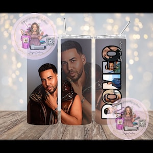 May include: Two stainless steel tumblers with a black and white image of a man on one and the name "Romeo Santos" on the other. The tumblers are on a wooden surface.
