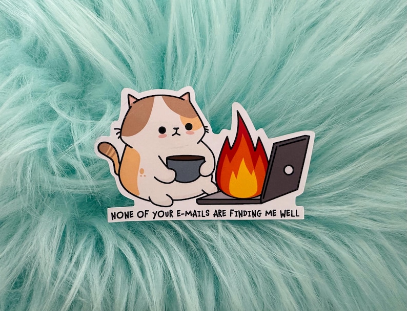 May include: A die-cut sticker featuring a cartoon cat with brown and white fur holding a dark grey mug. Next to the cat is a laptop with a large orange and red flame rising from the screen. The text reads: NONE OF YOUR E-MAILS ARE FINDING ME WELL.
