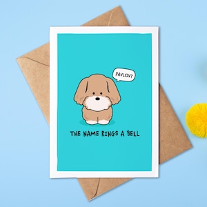 May include: A greeting card with a bright turquoise background featuring a cartoon light brown dog. A speech bubble above the dog says PAVLOV? and the text below reads THE NAME RINGS A BELL. The card is placed on a brown paper envelope.