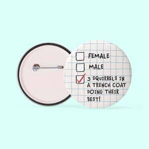 May include: A white button with a black and white grid pattern. The button has a checklist with three options: Female, Male, and 3 Squirrels in a Trench Coat Doing Their Best! The third option is checked.