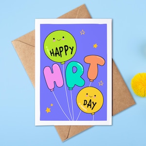May include: A greeting card with the words "HAPPY HRT DAY" on balloons. The balloons are green, pink, teal, and orange, with smiling faces. The card is on a brown envelope, with yellow pom-poms on a blue background.
