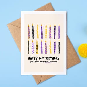 May include: A birthday card with the text "HAPPY 16TH BIRTHDAY YOU ONE OF A KIND FABULOUS HUMAN!" features colorful candles in black, yellow, and purple. The card is on a brown envelope, with yellow pom-poms on a blue background.
