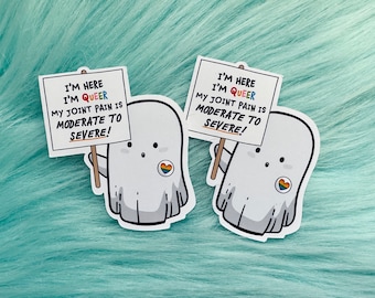 May include: Two white ghost stickers with rainbow hearts on their chests. Each ghost is holding a sign that reads "I'm here I'm queer My joint pain is moderate to severe!"