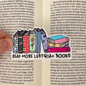 May include: A sticker with a rainbow colour scheme featuring a stack of books with the text "READ MORE LGBTQIA+ BOOKS".