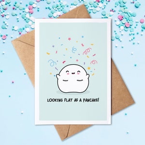 May include: A light blue greeting card with a white ghost illustration and confetti. The ghost has a happy face and is smiling. The text on the card reads "Looking flat as a pancake!"