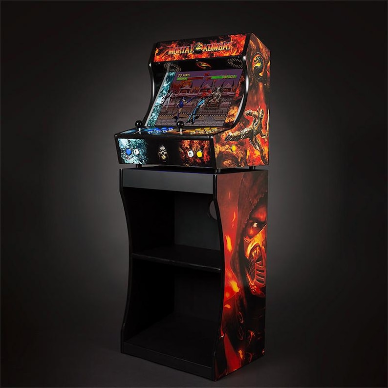 May include: A black arcade cabinet with a Mortal Kombat theme. The cabinet has a screen showing a game in progress. The cabinet is on a black stand with two shelves.