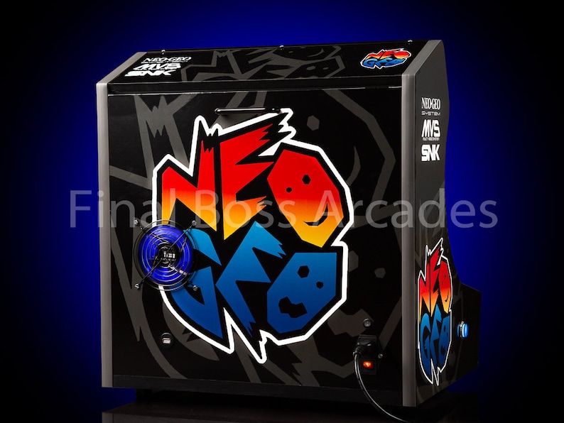 May include: A black arcade cabinet with a colourful "NEO GEO" logo on the front. The cabinet has a blue fan on the left side and a power cord plugged in on the right side. The text "NEO GEO MVS SNK" is printed on the right side of the cabinet.