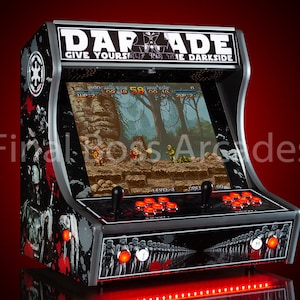 May include: A black and silver arcade cabinet with a Star Wars theme. The cabinet has a red LED light strip along the bottom and a screen displaying a video game. The cabinet is labelled "DARADE GIVE YOURSELF TO THE DARKSIDE".