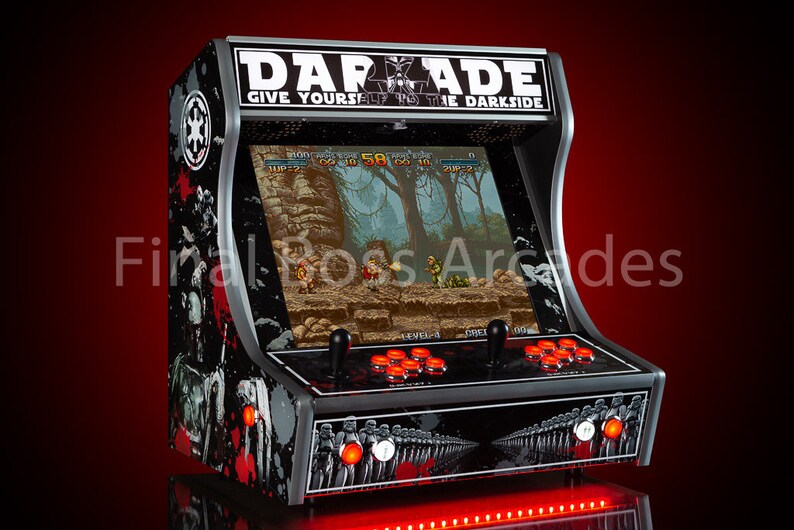 May include: A black and silver arcade cabinet with a Star Wars theme. The cabinet has a red LED light strip along the bottom and a screen displaying a video game. The cabinet is labelled "DARADE GIVE YOURSELF TO THE DARKSIDE".