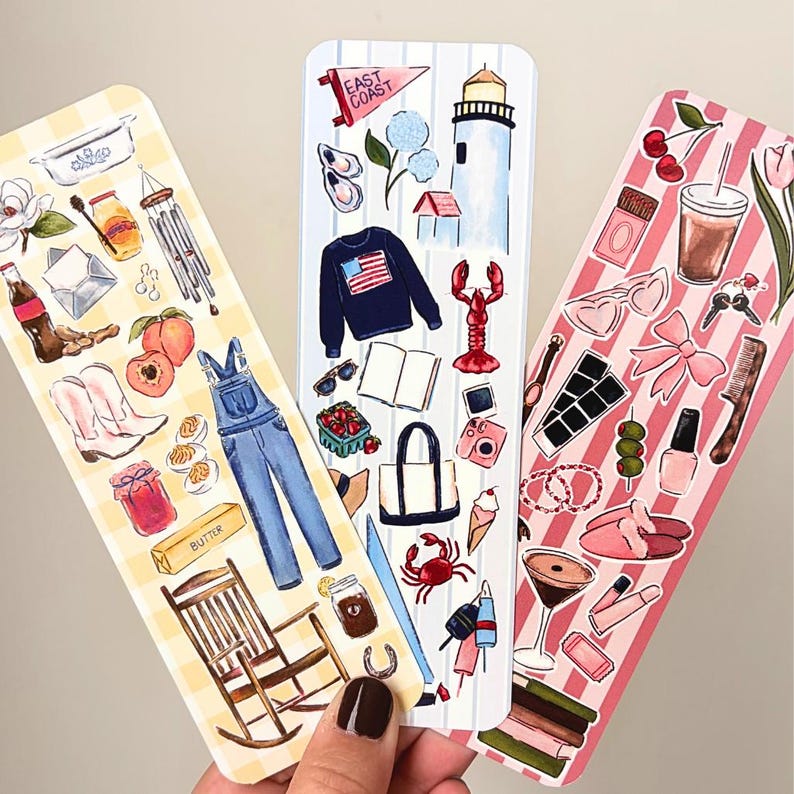 May include: Three decorative bookmarks with watercolor illustrations. One features a yellow gingham pattern with peaches, boots, and overalls. Another has a striped pattern with a lighthouse, lobster, and sweater. The third has a pink striped pattern with cherries and sunglasses.