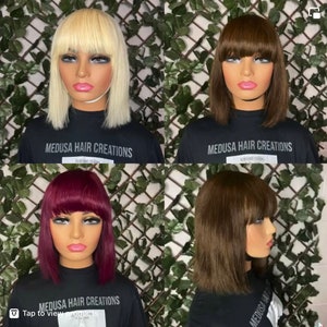Op de afbeelding: Vier verschillende bobpruiken met pony. De pruiken zijn blond, bruin, bordeauxrood en lichtbruin. De pruiken zijn gestyled op mannequins die zwarte shirts dragen met de tekst "MEDUSA HAIR CREATIONS" erop gedrukt. De afbeelding bevat de tekst "Tik om producten te bekijken".
