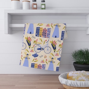 May include: A kitchen towel with a colorful pattern of houses, bicycles, windmills, and flowers. The text "hallo" is repeated throughout the design.