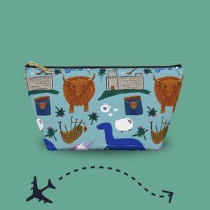 May include: A light blue cosmetic bag with a gold zipper, featuring a repeating pattern of Scottish icons. The design includes Highland cows, castles, bagpipes, and the Loch Ness Monster. The bag is a travel accessory.