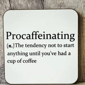 May include: A square white coaster with rounded corners. The coaster features the word "Procaffeinating" in black, with a definition below: "(n.) The tendency not to start anything until you've had a cup of coffee."