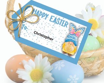 May include: Blue gift tag with white polka dots and the text "Happy Easter" and "to: Christopher". A cartoon gnome with a blue hat and pink bunny ears is in the bottom right corner of the tag. The tag is tied with a gold ribbon and is in a wicker basket with Easter eggs and daisies.