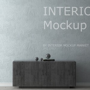May include: An interior mockup scene featuring a dark gray wooden dresser with six drawers, three decorative spheres, and a book. The text "INTERIOR Mockup" is displayed on the light blue textured wall. A vase with reeds is on the right.