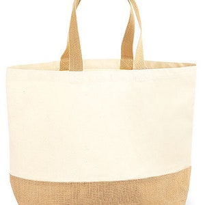 May include: Cream-colored tote bag with tan jute bottom and handles. The bag has a rectangular shape with a wide opening and two sturdy handles. The text "Tasche L" is printed in black script on the bottom right corner.