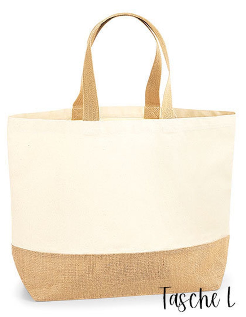 May include: Cream-colored tote bag with tan jute bottom and handles. The bag has a rectangular shape with a wide opening and two sturdy handles. The text "Tasche L" is printed in black script on the bottom right corner.