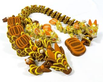 May include: A whimsical, handcrafted dragon sculpture in shades of brown, yellow, and orange. The dragon features pumpkin-shaped accents and intricate detailing, perfect for fall decor or fantasy enthusiasts.