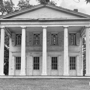 May include: A black and white photo of a large, white, wooden building with a porch and columns. The building has five windows with shutters and the words "CREATE", "GATHER", "LEARN", and "INSPIRE" written on the windows.
