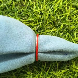 Peut inclure: Une bague rouge et argent avec une fine bande rouge.