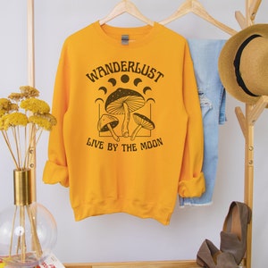 May include: Yellow sweatshirt with a black graphic of mushrooms and the text "Wanderlust Live by the Moon".