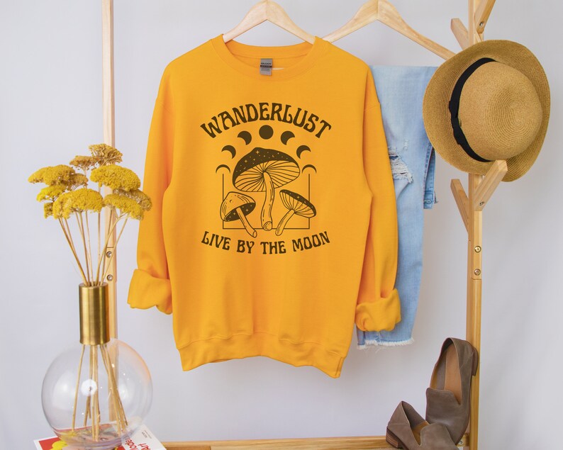 May include: Yellow sweatshirt with a black graphic of mushrooms and the text "Wanderlust Live by the Moon".