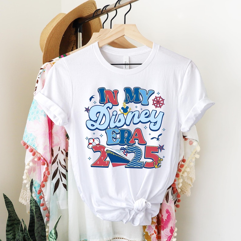 Puede incluir: Camiseta blanca con un gr&aacute;fico colorido que dice "In My Disney Era 2025". El gr&aacute;fico incluye una cabeza de Mickey Mouse, un barco y una br&uacute;jula.