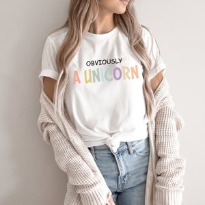 May include: White t-shirt with the text "OBVIOUSLY A UNICORN" in rainbow colors.
