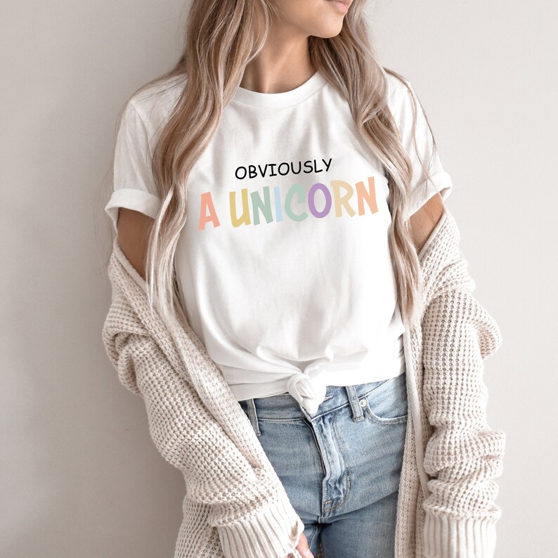 May include: White t-shirt with the text "OBVIOUSLY A UNICORN" in rainbow colors.