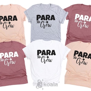 Op de afbeelding: Een verzameling van zes t-shirts in verschillende kleuren, waaronder perzik, grijs, wit en bordeauxrood. Elk shirt heeft de tekst "PARA Crew" in een vetgedrukte, zwarte letter met een pijldesign. De shirts zijn korte mouwen.
