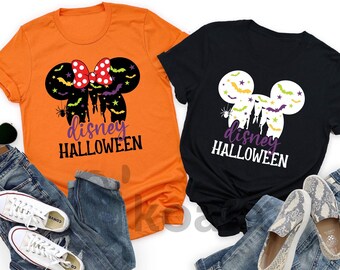May include: Two t-shirts, one orange and one black, with a Halloween-themed design. The design features a Mickey Mouse silhouette with bats, stars, and the text "disney HALLOWEEN". The shirts are paired with jeans, shoes, and sunglasses.