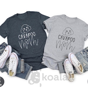 May include: Two t-shirts, one dark heather grey and one light grey, with the text "Cavapoo Mom" and a doodle of a cavapoo dog.