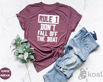 May include: Heather maroon t-shirt with white text that reads "RULE 1 DON'T FALL OFF THE BOAT".