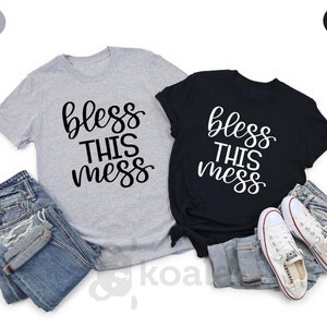 Puede incluir: Dos camisetas con el texto "Bless this mess" en letras blancas y negras. Las camisetas son de color gris claro y negro.