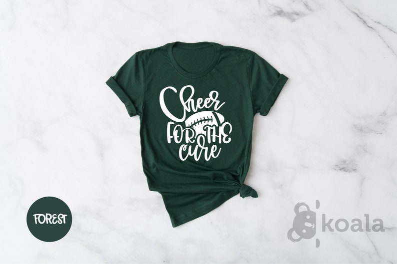 May include: A dark green t-shirt with the text "Cheer for the cure" in white lettering and a white football graphic.