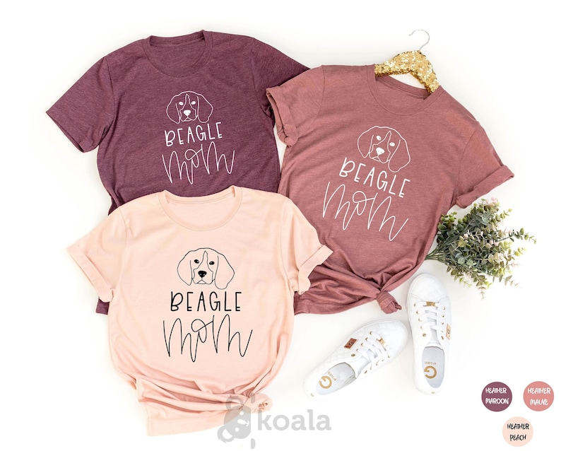 May include: Three t-shirts with the text "BEAGLE MOM" in black script and a line drawing of a beagle dog's head. The shirts are in heather maroon and heather peach.