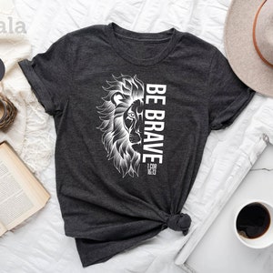 May include: Dark gray heather t-shirt with a white lion graphic and the text "Be Brave 1 Cor 16:13".