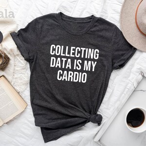 Pu&ograve; includere: T-shirt in jersey melange grigio scuro con testo bianco che recita "COLLECTING DATA IS MY CARDIO".