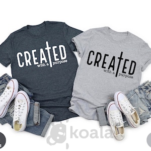 May include: Two t-shirts, one dark heather gray and one light gray, with the text "CREATED with a purpose" and a cross graphic.