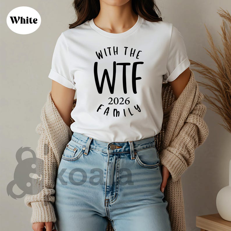 A woman wearing a white t-shirt with the text "With the WTF 2016 Family" printed on it, paired with blue jeans and a beige cardigan.