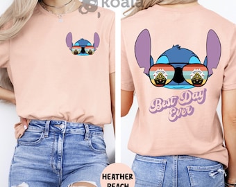 Op de afbeelding: Een heideperzikkleurig t-shirt met een blauw Stitch-personage dat een zonnebril draagt met een cruise-schipreflectie. De achterkant van het shirt heeft hetzelfde Stitch-personage met de tekst "Best Day Ever" in een retro-lettertype.