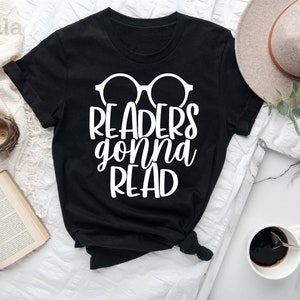 May include: Black t-shirt with white text that reads "Readers gonna read" and a pair of glasses graphic.