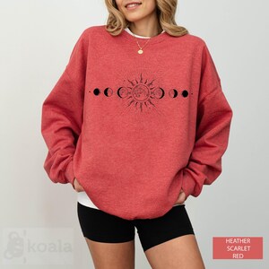 a woman wearing a red sweatshirt with the phases of the moon on it