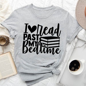 May include: A light gray t-shirt with the text "I ♥ read past my bedtime" in black. A stack of books is pictured next to the text.