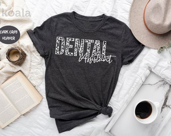 May include: Dark gray heather t-shirt with white text that reads "DENTAL Assistant" in a leopard print font.