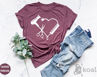 May include: Maroon t-shirt with a white graphic of a heart made of a hairdryer, comb, and scissors, with a power plug. The shirt is paired with blue jeans. The words "Heather Maroon" are in a circle.