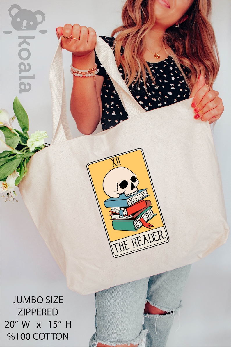 May include: A white canvas tote bag with a zipper closure. The bag features a graphic of a tarot card, The Reader, with a skull and books. The bag is 20 inches wide and 15 inches high and is made of 100% cotton.